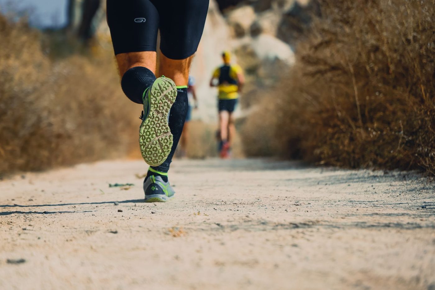 Trail runners' legs and shoes in motion on a dirt trail